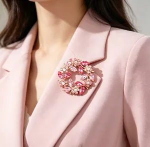Detailed view of an elegant pink crystal floral wreath brooch on a pink blazer.