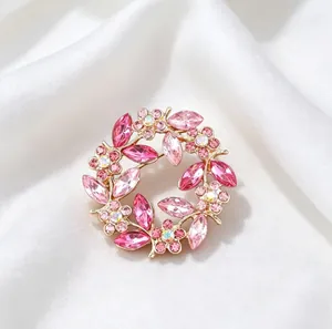 Close-up detail of elegant vintage crystal wreath brooch with pink rhinestones on white silk