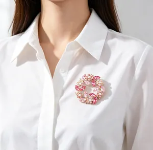 Detailed view of an elegant pink crystal floral wreath brooch on a white collared shirt