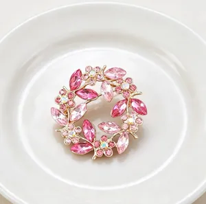 Detailed macro shot of a vintage pink crystal flower wreath brooch on a white plate