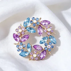 Elegant vintage crystal wreath brooch with blue and purple rhinestones on white silk