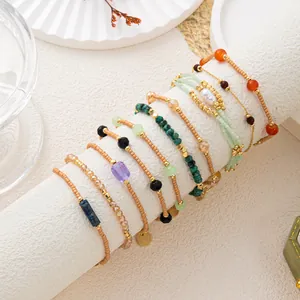Detalle de set de pulseras vintage en capas con cuentas de piedra y tonos oro.