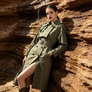 Stylish olive green long trench coat worn by model in a rocky desert landscape detail