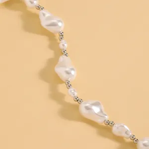 Detailed macro view of baroque irregular pearls with silver beads on a beige background