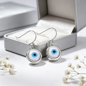 Dettaglio orecchini pendenti Evil Eye in acciaio al titanio argento su portagioie