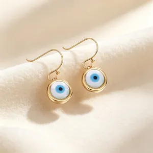 Primo piano dettagliato di eleganti orecchini a cerchio dorati Evil Eye su tessuto morbido