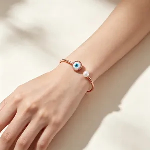 Vista dettagliata di un bracciale a cerchio minimalista con malocchio e perla in oro rosa al polso