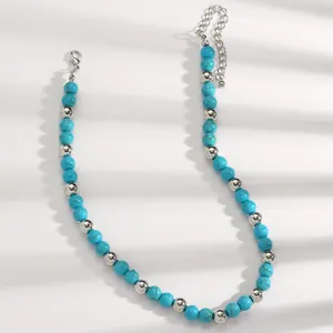 Close-up of bohemian turquoise and silver beaded necklace on white background with shadows.