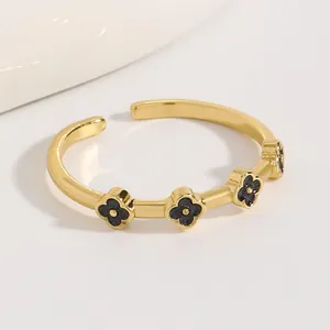 Primo piano di un anello aperto in acciaio inossidabile dorato con motivi a quadrifoglio neri