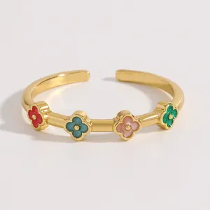 Dettaglio di anello aperto in acciaio dorato con motivi a quadrifoglio colorati