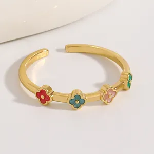 Primo piano di un anello regolabile in acciaio dorato con motivi a quadrifoglio colorati.