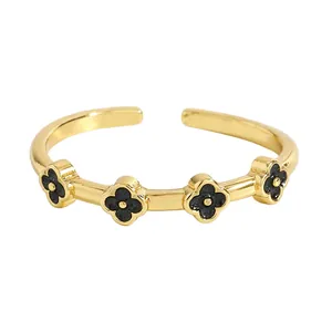 Dettaglio dell'anello aperto in acciaio inossidabile dorato con quadrifogli neri eleganti.