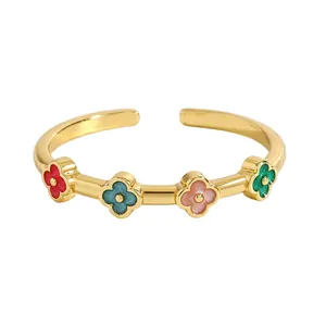 Primo piano di un anello aperto in acciaio dorato con quattro motivi a quadrifoglio colorati