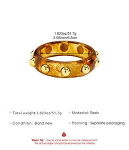 Detail view of vintage amber resin bangle with gold studs and measurements