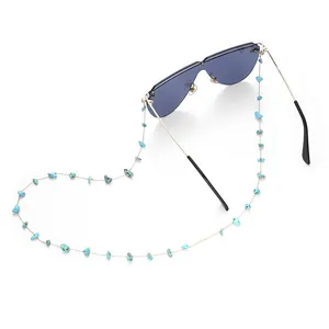 Macro detail of natural turquoise stones on a slim golden eyeglass chain attached to sunglasses