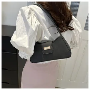 Back view of a woman wearing a black vintage baguette shoulder bag with a gold buckle.