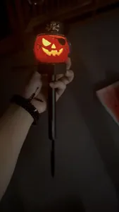 Detailed view of a glowing solar Halloween pirate pumpkin stake light in a dark setting