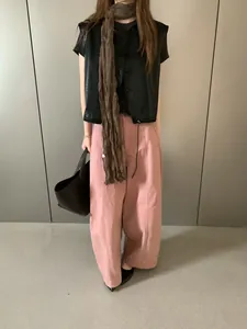 Dettaglio di un elegante gilet in pelle nera vintage con una lunga sciarpa marrone integrata.