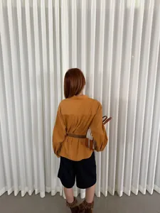 Vista posteriore di una camicia retrò in velluto a coste marrone senape da donna