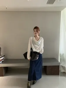 Haut élégant blanc à manches longues et col drapé dans un décor minimaliste chic