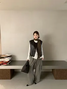Dettaglio dell'elegante gilet in pelle nera con sciarpa in una camera chic e minimal