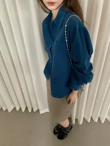 Dettaglio di una camicia vintage in velluto a coste blu da donna con gonna color kaki