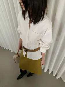 Vista dettagliata di una camicia bianca a maniche lunghe in velluto con cintura e gonna