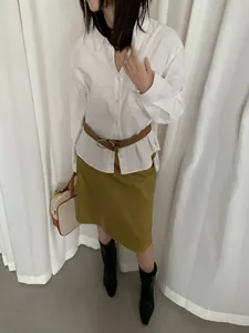 Modella che indossa una camicia in velluto a coste bianco a maniche lunghe e cintura