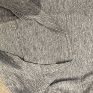 Détail rapproché du tissu en maille chiné gris d'un haut élégant à manches longues