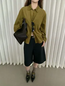 Scatto a figura intera di una camicia in velluto a coste senape con pantaloncini neri