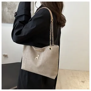 Dettaglio di una borsa tote vintage in camoscio beige con tracolla a catena oro.