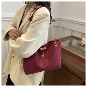 Elegante borsa tote in pelle scamosciata bordeaux con catena d'oro mostrata sul modello