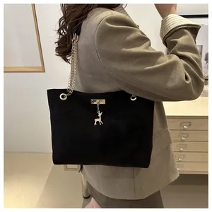 Dettaglio di borsa tote nera vintage in similpelle con catena oro e ciondolo cervo