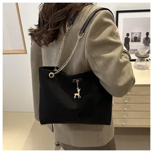 Dettaglio di una borsa tote vintage nera con catena e ciondolo a forma di cervo.