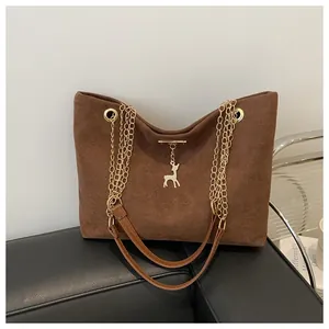 Vista dettagliata della borsa tote in camoscio marrone con catene d'oro e ciondolo a cervo