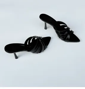 Detalle de sandalias tipo mule negras con punta fina y elegantes tiras cruzadas