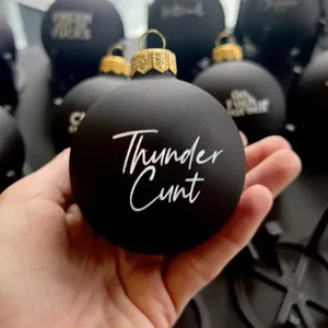 Vue détaillée d'une boule de Noël noire mate avec un texte humoristique en blanc