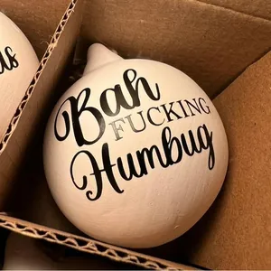 Detail view of a white ceramic Christmas bauble with humorous offensive text Bah Fucking Humbug