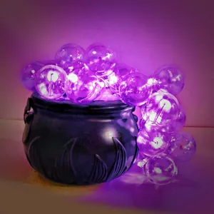 Close-up of Halloween witch cauldron with glowing purple bubble string lights