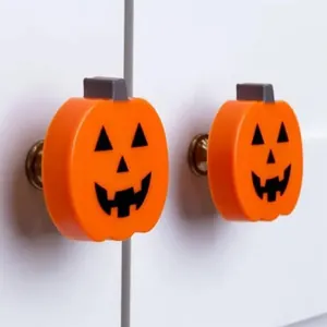 Detailansicht festlicher orangefarbener Kürbis-Türknöpfe an weißen Schranktüren für Halloween
