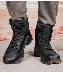 Detail view of durable black men's tactical hiking boots on a sandy outdoor terrain.