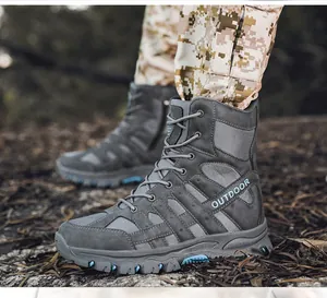 Detailed view of men's grey high-top tactical combat boots in a rugged outdoor environment.