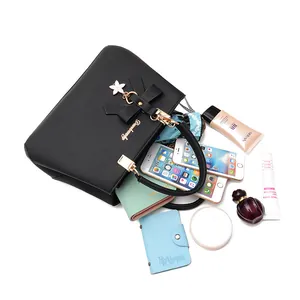 Elegante schwarze Handtasche aus Kunstleder mit Schleifenanhänger und Alltagsgegenständen