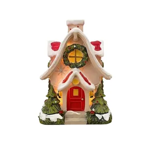 Miniature light-up Christmas house ornament with snow-capped roof and wreath