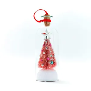 Detailopname van een roze miniatuurkerstboom in een decoratieve glazen fles met kurk