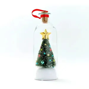 Mini kerstboom in een glazen fles met een rood lint en een stralende gouden ster erop