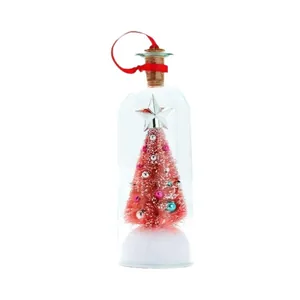 Roze mini kerstboom in glazen flesje met rood lint om op te hangen