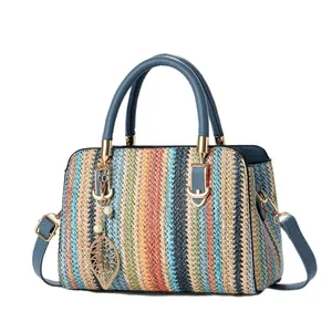 Bolso de mano tejido a rayas de colores con colgante de hoja dorada y correa azul