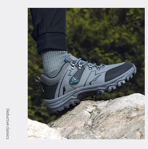Close-up of a men's gray hiking shoe stepping on a rock in a forest setting