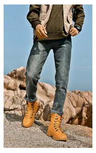 High-top yellow tactical boots for men worn on rocky outdoor terrain for hiking.